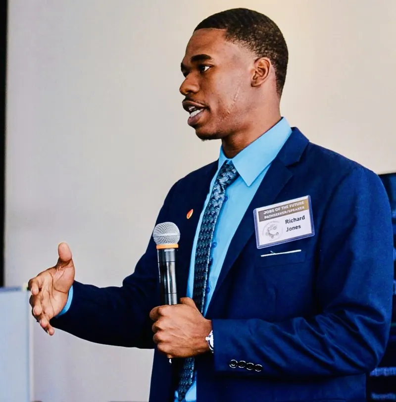 Richard Jones speaking with a microphone at AyZar Outreach's Jobs of the Future Summit